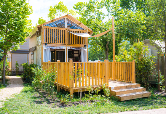 Afbeelding van een gezellige houten lodge bij Air Lodge met zonnig terras, omgeven door groen.