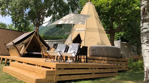 Tenda tipi Tipi Lodge su una pedana in legno con sedie e vasca idromassaggio a Lago Idro Glamping Boutique, Italia.