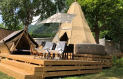 Tenda tipi Tipi Lodge su una pedana in legno con sedie e vasca idromassaggio a Lago Idro Glamping Boutique, Italia.