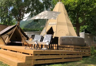 Tenda tipi Tipi Lodge su una pedana in legno con sedie e vasca idromassaggio a Lago Idro Glamping Boutique, Italia.