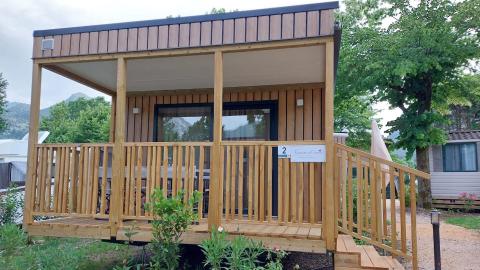 Chalet “Next XL” Loggia bij Lago Idro Glamping Boutique in Italië, met houten veranda en omgeven door groen.