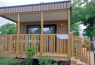Chalet “Next XL” Loggia bij Lago Idro Glamping Boutique in Italië, met houten veranda en omgeven door groen.