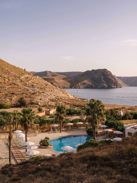 Vista de la piscina en Wecamp Cabo de Gata, rodeada de montañas y mar en Andalucía, España.
