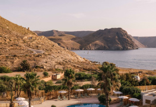 Uitzicht op het zwembad bij Wecamp Cabo de Gata vakantiepark met bergen en zee in Andalusië, Spanje.