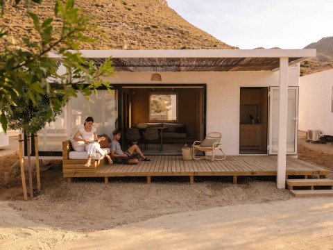 To personer slapper af på terrassen foran en moderne hytte i Wecamp Cabo de Gata, Andalusien, Spanien.