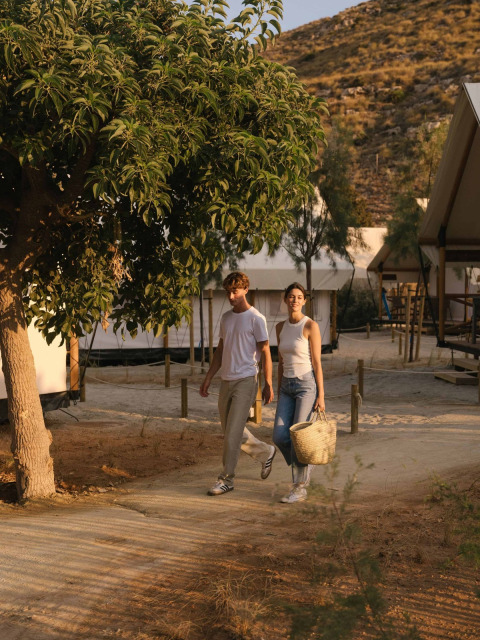 Een koppel wandelt bij Wecamp Cabo de Gata, een vakantieresort in Andalusië, Spanje, tussen de tenten.
