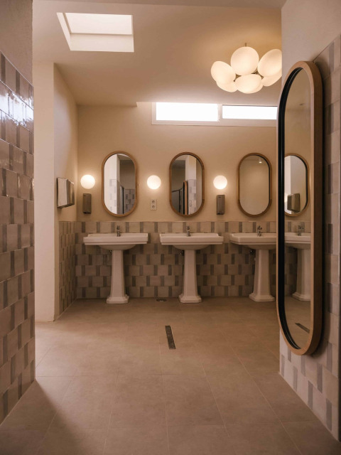 Modern toilet met drie wastafels en ovale spiegels in Wecamp Cabo de Gata, Andalusië, Spanje.