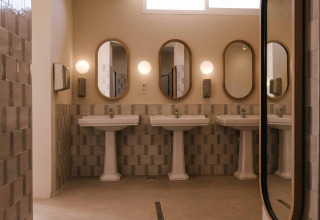Modernes Badezimmer mit drei Waschbecken und ovalen Spiegeln im Wecamp Cabo de Gata, Andalusien, Spanien.