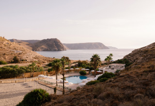 Udsigt over ferieparken Wecamp Cabo de Gata i Andalusien, Spanien, med pool, bjerge og havet i baggrunden.