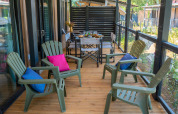 Terrazza in legno con sedie verdi e cuscini colorati presso Cottage Next XXL Prestige, Trasimeno Glamping Resort, Italia.