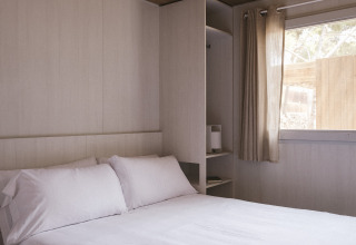 Slaapkamer in de MOBIL HOME FAMILY WOOD bij Wecamp Cala Montgó, Spanje met tweepersoonsbed en houten plafond.