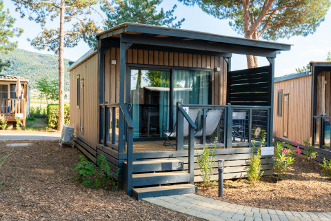 Cube Suite XL lodge met houten bekleding, gemeubileerd terras en groene natuuromgeving.