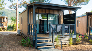 Cube Suite XL lodge con pannelli in legno, terrazza arredata e ambiente naturale verde.