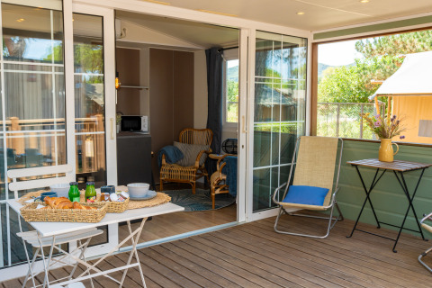 Terraza exterior en la Cottage Classic Suite del Trasimeno Glamping Resort en Italia, con desayuno y sillas.