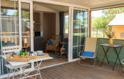 Terrazza esterna della Cottage Classic Suite al Trasimeno Glamping Resort in Italia, con colazione e sedie.