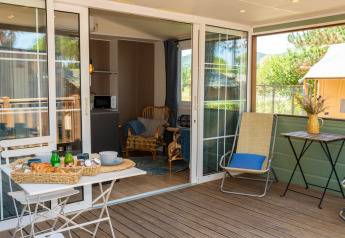 Terraza exterior en la Cottage Classic Suite del Trasimeno Glamping Resort en Italia, con desayuno y sillas.