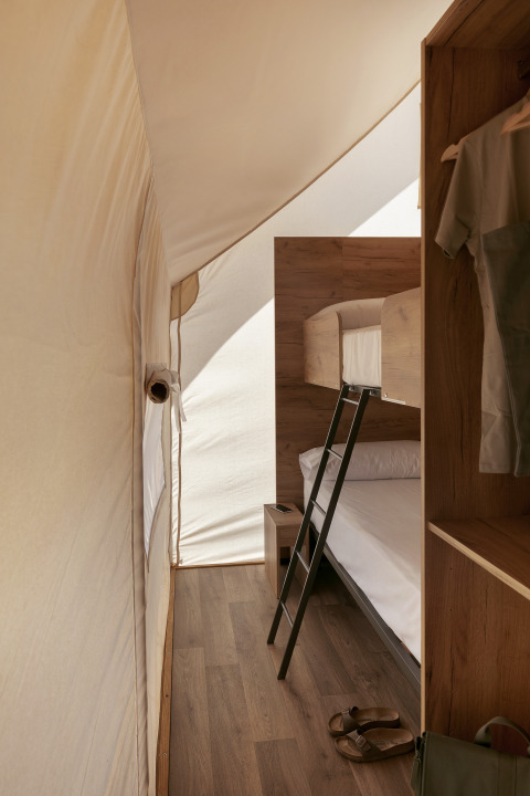 Intérieur d'une tente safari Glamping Family au Wecamp Cabo de Gata en Espagne, avec lits superposés et sol en bois.