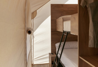 Interior de una tienda safari Glamping Family en Wecamp Cabo de Gata, España, con literas y suelo de madera.