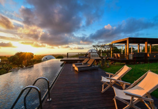 Piscina infinita y tumbonas al atardecer en Wecamp Reserva Alecrim, un parque vacacional en Alentejo, Portugal.