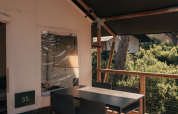 Buiten eethoek op het terras van een safaritent, met moderne stoelen en uitzicht op de natuur.
