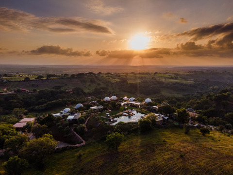 Vista al atardecer del parque vacacional Wecamp Reserva Alecrim en Alentejo, Portugal, con colinas verdes.