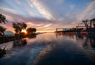 Atardecer en la piscina infinita de Wecamp Reserva Alecrim, rodeada de naturaleza en Alentejo, Portugal.