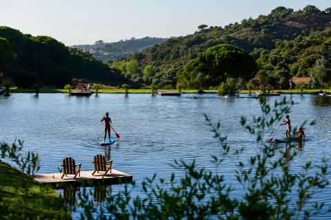 Le parc de vacances Wecamp Reserva Alecrim en Alentejo, Portugal, avec des gens pagayant sur un lac paisible.