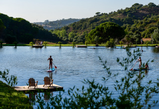 Parque vacacional Wecamp Reserva Alecrim en Alentejo, Portugal, con personas haciendo paddle surf en un lago.