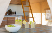 Interieur van een glamping tent bij Wecamp Cádiz, Spanje, met tafel, limonade, druiven, keuken en slaapzolder.