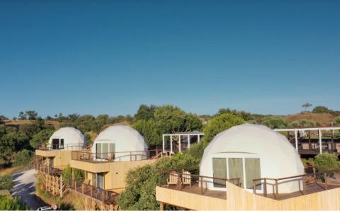 Koepelhuisjes op houten terrassen bij Dome House, Wecamp Reserva Alecrim, Portugal, in natuurlijke omgeving.