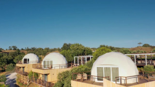 Koepelhuisjes op houten terrassen bij Dome House, Wecamp Reserva Alecrim, Portugal, in natuurlijke omgeving.