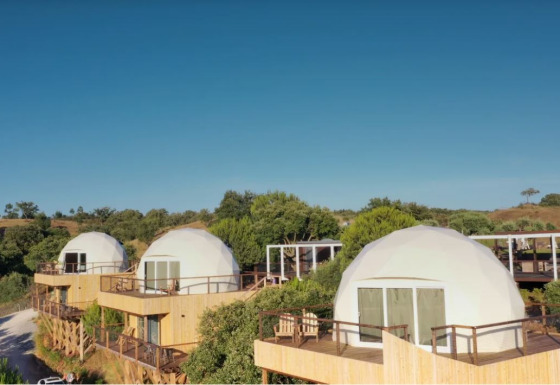 Koepelhuisjes op houten terrassen bij Dome House, Wecamp Reserva Alecrim, Portugal, in natuurlijke omgeving.