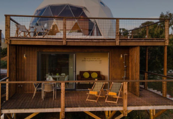 Dome House Duplex en Wecamp Reserva Alecrim, Portugal, con dos terrazas de madera y asientos exteriores.