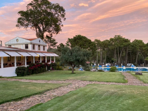 Wecamp Sao Miguel en Alentejo, Portugal : parc de vacances avec pelouse, piscine, arbres et coucher de soleil.