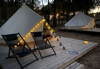Twee tenten met lichtjes en twee stoelen op houten terras bij zonsondergang in Wecamp Sao Miguel, Alentejo.