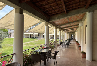 Overdækket terrasse med caféborde og stole ved Wecamp Sao Miguel feriested i Alentejo, Portugal.