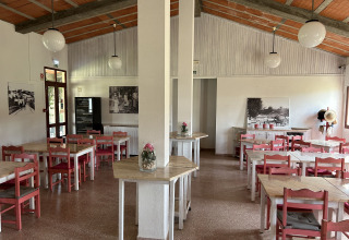 Lichte eetzaal met rode stoelen bij Wecamp Sao Miguel vakantiedomein in Alentejo, Portugal.