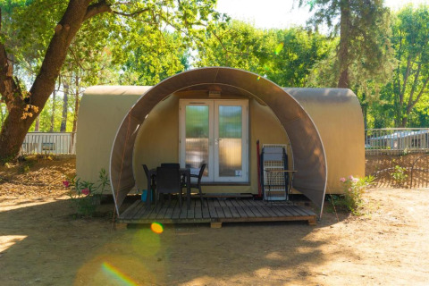 Buitenaanzicht van de Coco Suite Airo safaritent met overdekt terras, tuinset en omringende bomen.