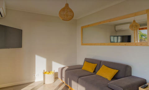 Woonkamer van Bungalow Comfort Family bij Wecamp Reserva Alecrim, Portugal, met zetel en gele kussens.
