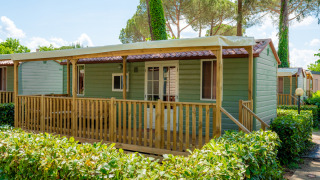 Photo d’un lodge confortable avec véranda en bois et verdure, parfait pour un séjour détente en plein air.