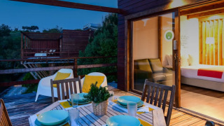Vista nocturna de la terraza en el Bungalow «Compact Wood» de Wecamp Reserva Alecrim, Portugal, con mesa exterior.