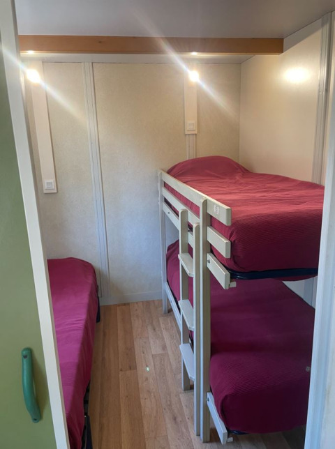 Familiekamer met stapelbedden en enkel bed, houten vloer en lichte muren in Bungalow Family, Wecamp Sao Miguel, Portugal.