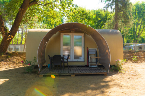 Safari tent Coco Suite Lake met terras, stoelen en tafel, gelegen tussen bomen en natuur.