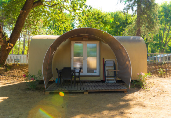 Safari tent Coco Suite Lake met terras, stoelen en tafel, gelegen tussen bomen en natuur.