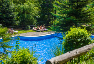 Piscina all'aperto con persone che si rilassano tra il verde al campeggio Bedura Park in Catalogna, Spagna.