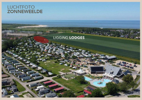 Luchtfoto van Camping Zonneweelde met zicht op de lodges, het zwembad en het strand in de buurt.