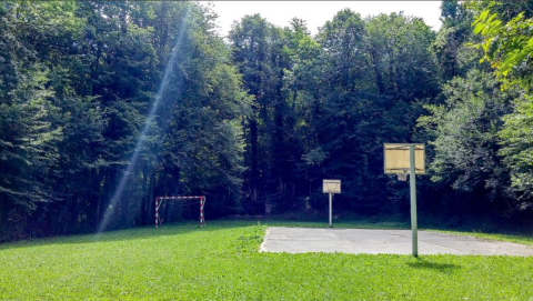 Campo sportivo all'aperto tra i boschi con canestri e porta presso il campeggio Bedura Park in Catalogna.