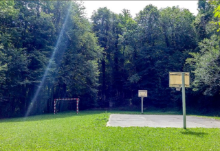 Campo sportivo all'aperto tra i boschi con canestri e porta presso il campeggio Bedura Park in Catalogna.