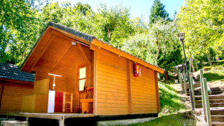 Casetta di legno immersa tra alberi verdi e sole, vicino a una scalinata, ambiente tranquillo.