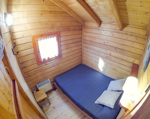 Cozy wooden bedroom with double bed in Bungalow Comfort cabin at Campsite Bedura Park in Spain, well-lit.